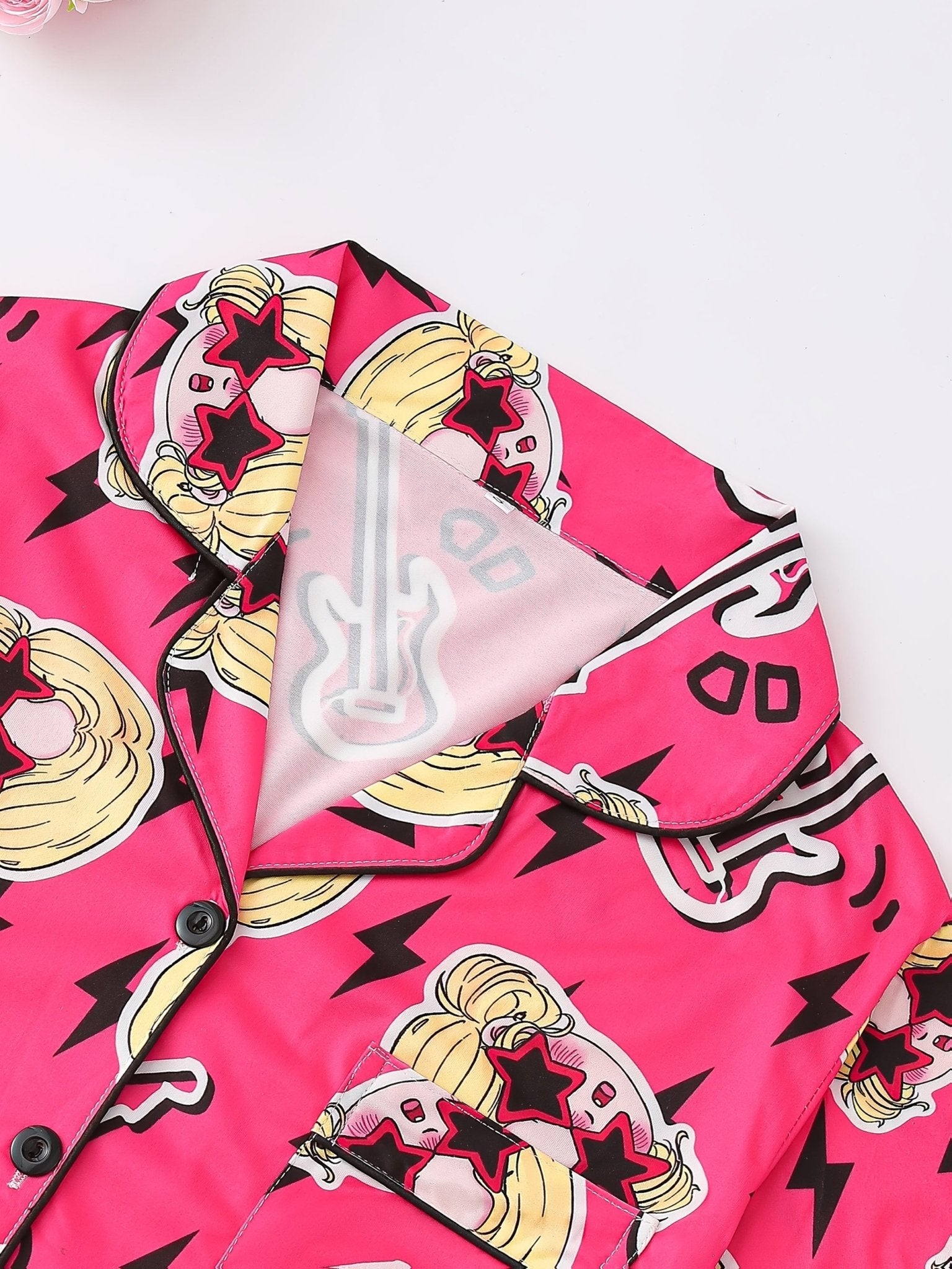 Bright pop-pink satin-look short-sleeve pajama set with guitar and star-sunglasses print, piped trim, chest pocket and elastic waist shorts in 95% Polyester 5% Elastane — silky stretch travel-ready loungewear