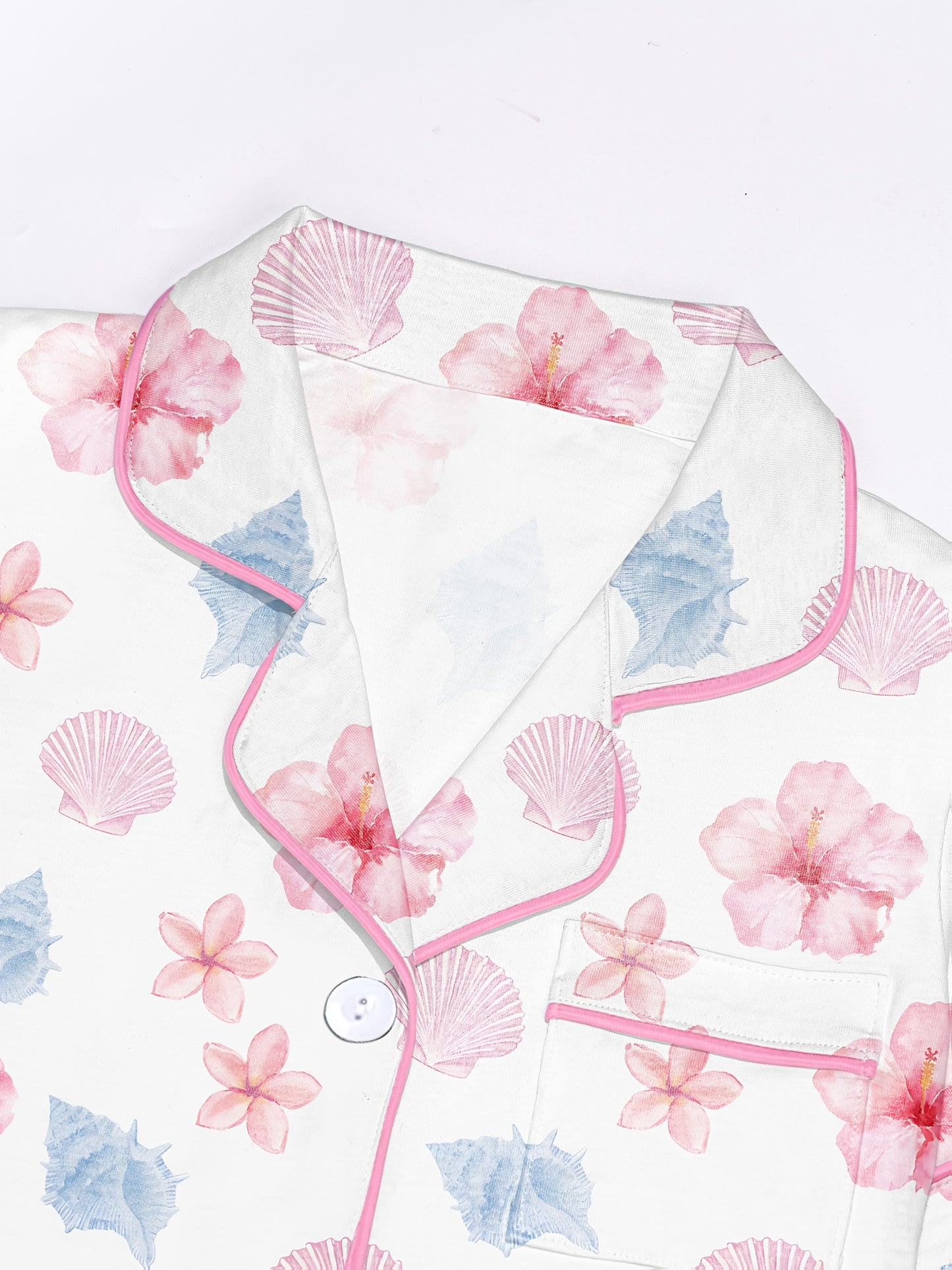White modal pajama set with pastel seashell and hibiscus print — short sleeve button top and elastic waist shorts with piping