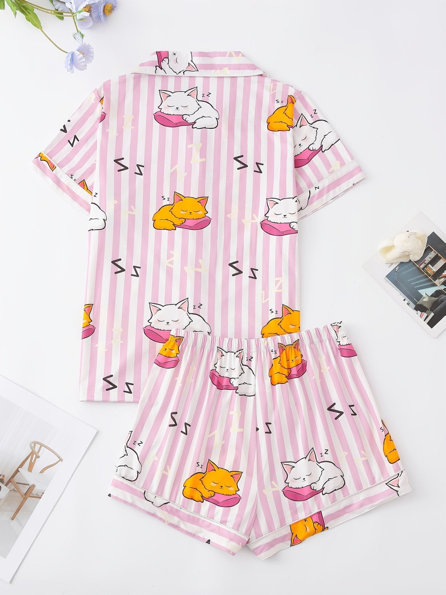 Pink stripe satin-look short-sleeve pajama set with orange and white sleeping cat print, piped trim, chest pocket and elastic waist shorts in 95% Polyester 5% Elastane — silky stretch travel-ready loungewear