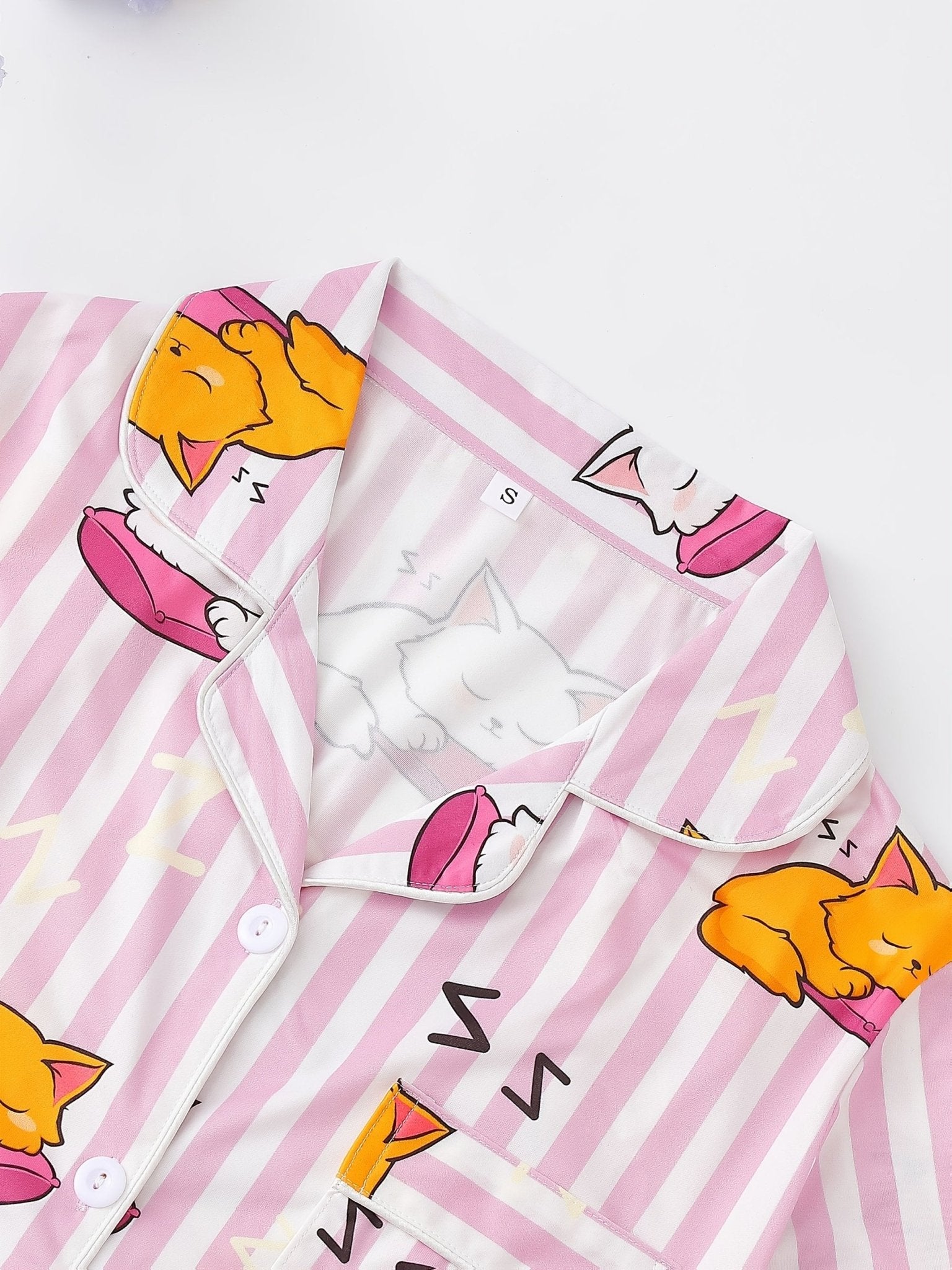 Pink stripe satin-look short-sleeve pajama set with orange and white sleeping cat print, piped trim, chest pocket and elastic waist shorts in 95% Polyester 5% Elastane — silky stretch travel-ready loungewear