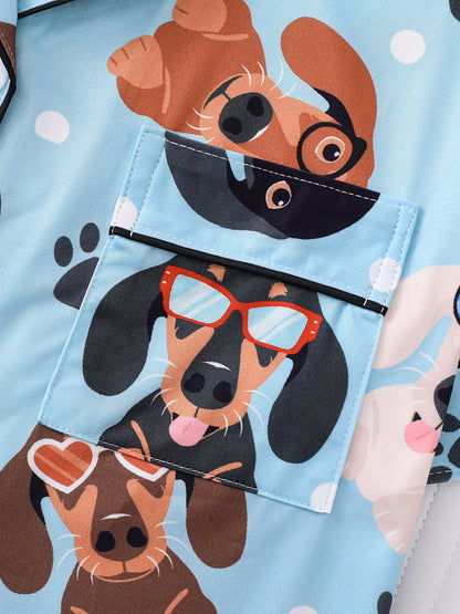 Sky-blue satin-look pajama set with playful dachshund and paw-print pattern — short-sleeve button-up top with chest pocket and elastic waist shorts, 95% Polyester/5% Elastane