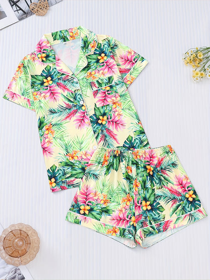 Cream satin-look pajama set with vibrant tropical floral and palm leaf print — short-sleeve button-up top with chest pocket and elastic waist shorts, 95% Polyester/5% Elastane