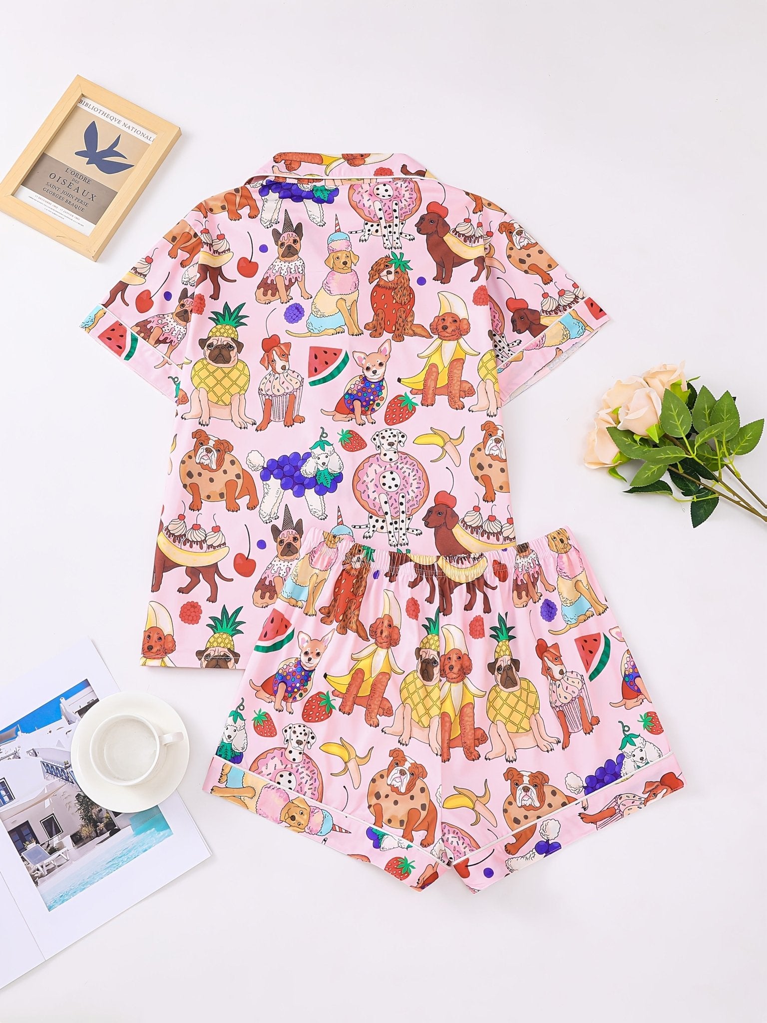 Pink satin-look short-sleeve pajama set with colorful puppy and fruit print, piped trim, chest pocket and elastic waist shorts in 95% Polyester 5% Elastane — silky stretch travel-ready loungewear