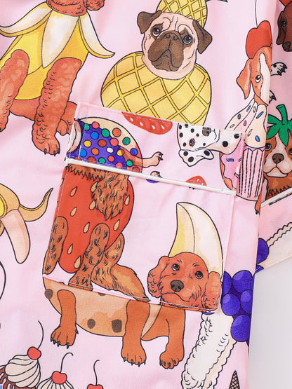 Pink satin-look short-sleeve pajama set with colorful puppy and fruit print, piped trim, chest pocket and elastic waist shorts in 95% Polyester 5% Elastane — silky stretch travel-ready loungewear