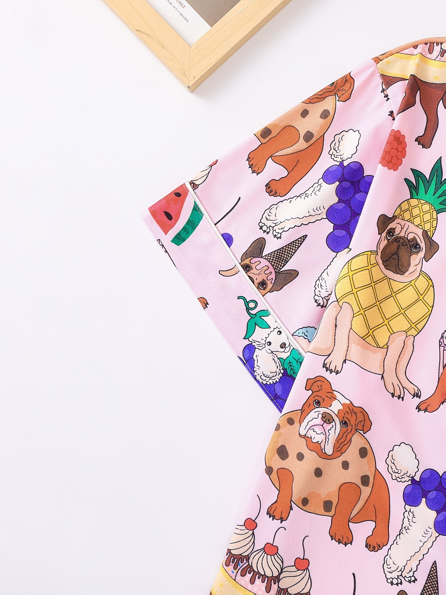 Pink satin-look short-sleeve pajama set with colorful puppy and fruit print, piped trim, chest pocket and elastic waist shorts in 95% Polyester 5% Elastane — silky stretch travel-ready loungewear