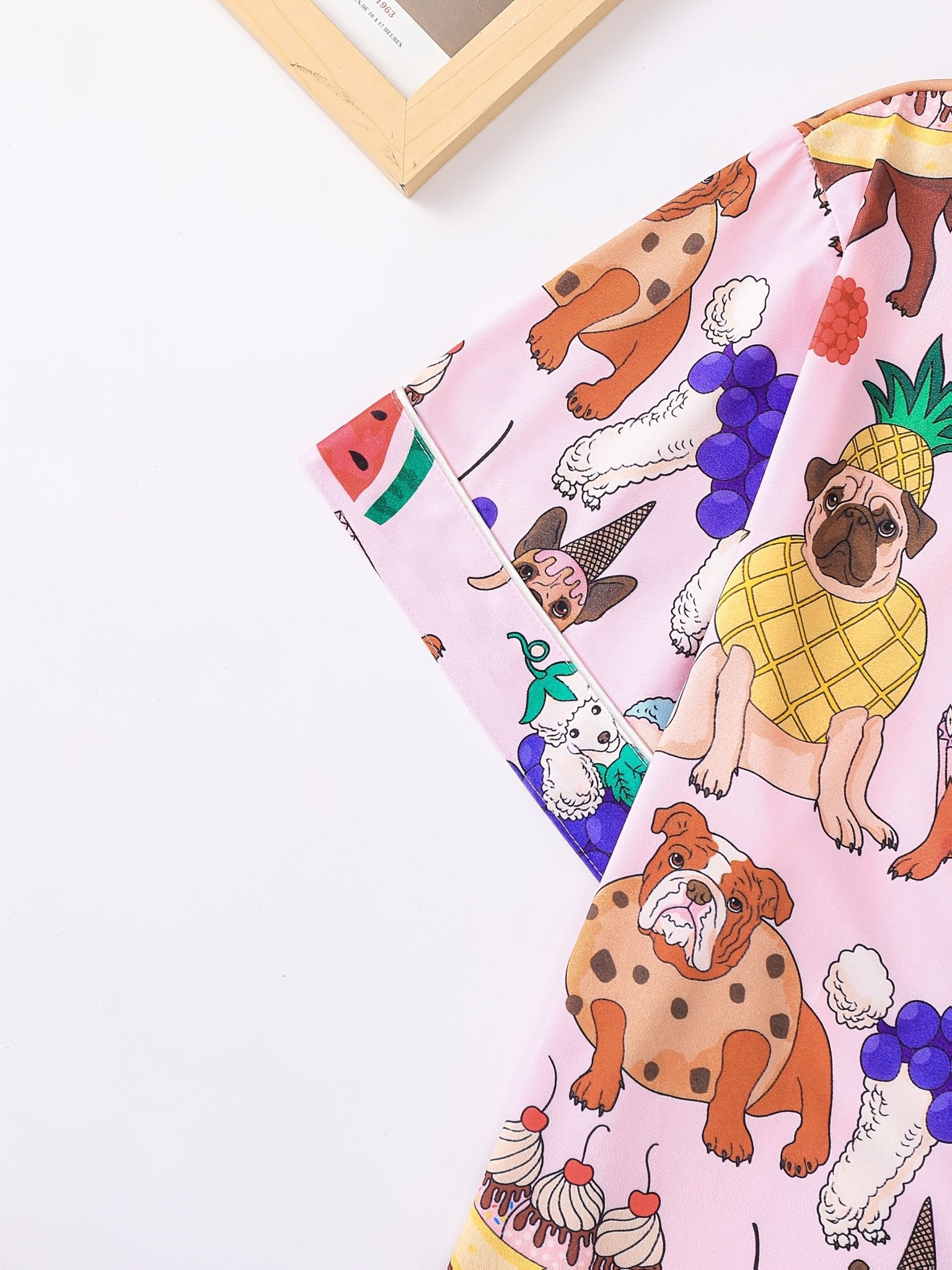 Pink satin-look short-sleeve pajama set with colorful puppy and fruit print, piped trim, chest pocket and elastic waist shorts in 95% Polyester 5% Elastane — silky stretch travel-ready loungewear