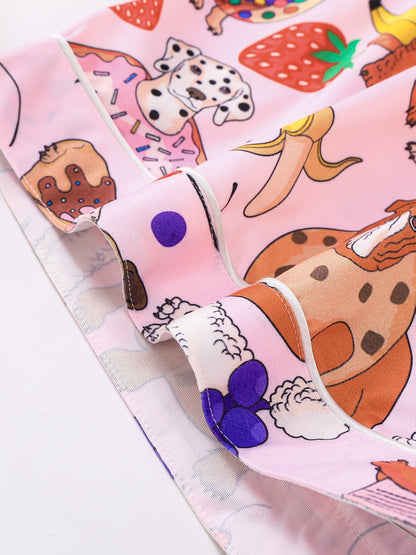 Pink satin-look short-sleeve pajama set with colorful puppy and fruit print, piped trim, chest pocket and elastic waist shorts in 95% Polyester 5% Elastane — silky stretch travel-ready loungewear