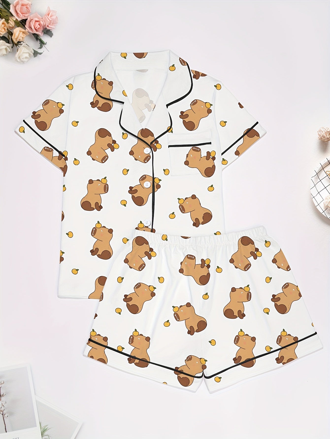 White short-sleeve pajama set with brown bear and yellow pear print — button-up top and elastic waist shorts with black piping
