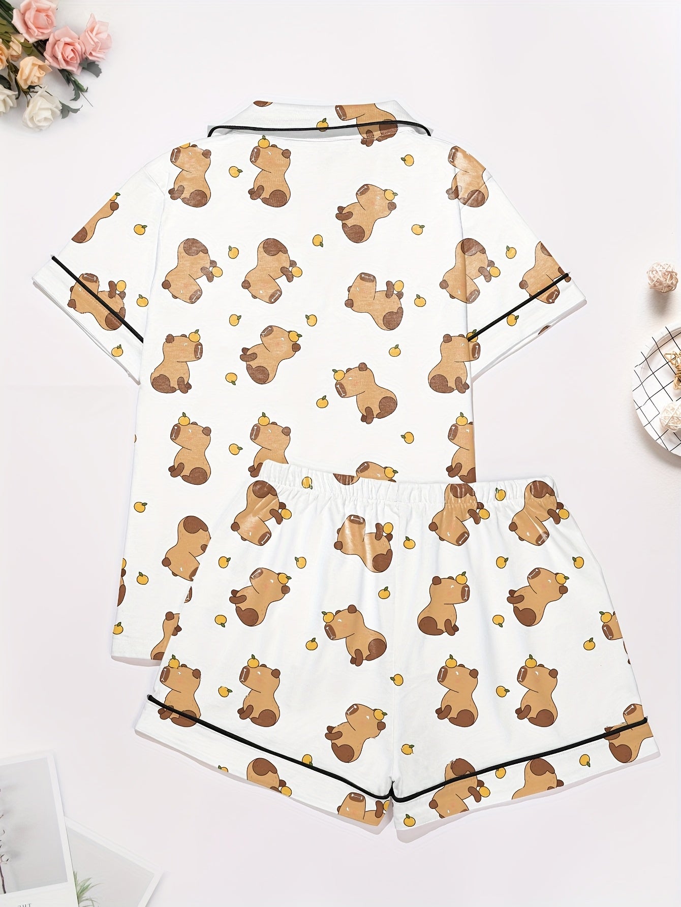 White short-sleeve pajama set with brown bear and yellow pear print — button-up top and elastic waist shorts with black piping