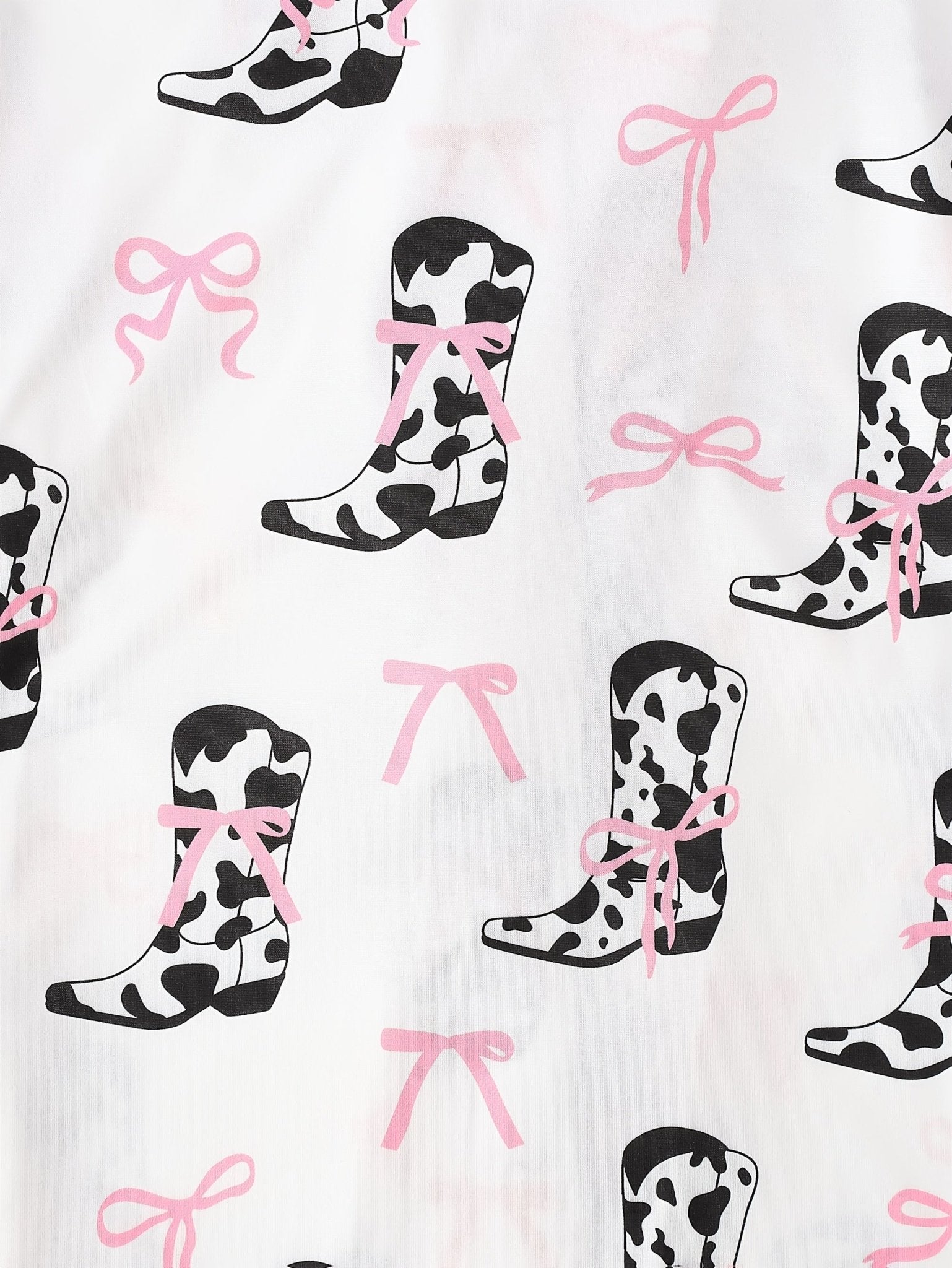 White cow-print short-sleeve pajama set with pink bow accents in silky 95% Polyester 5% Elastane, featuring chest pocket and elastic waist shorts